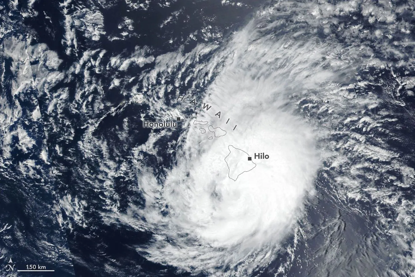 The spiraling clouds of a hurricane appear near the Hawaiian Islands. Its eye is just south of the Island of Hawaiʻi.